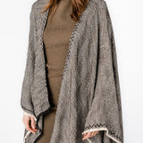 Poncho mit schwarzem Linienmuster.