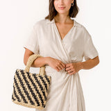 Gestreifte schwarze und beige geflochtene Handtasche.