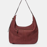 Schultertasche aus weinrotem Veloursleder.