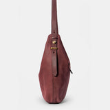 Schultertasche aus weinrotem Veloursleder.