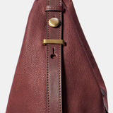 Schultertasche aus weinrotem Veloursleder.