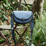 Halbmond-Umhängetasche aus recycelten Materialien in Blau.