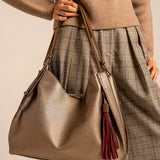 Schultertasche mit ockerfarbenem Anhänger.