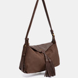 Schultertasche mit braunem Quasten-Anhänger.