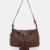 Schultertasche mit braunem Quasten-Anhänger.