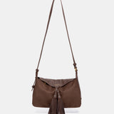 Schultertasche mit braunem Quasten-Anhänger.