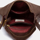 Schultertasche mit braunem Quasten-Anhänger.