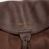 Schultertasche mit braunem Quasten-Anhänger.