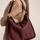 Burgundy shoulder bag made from recycled materials.